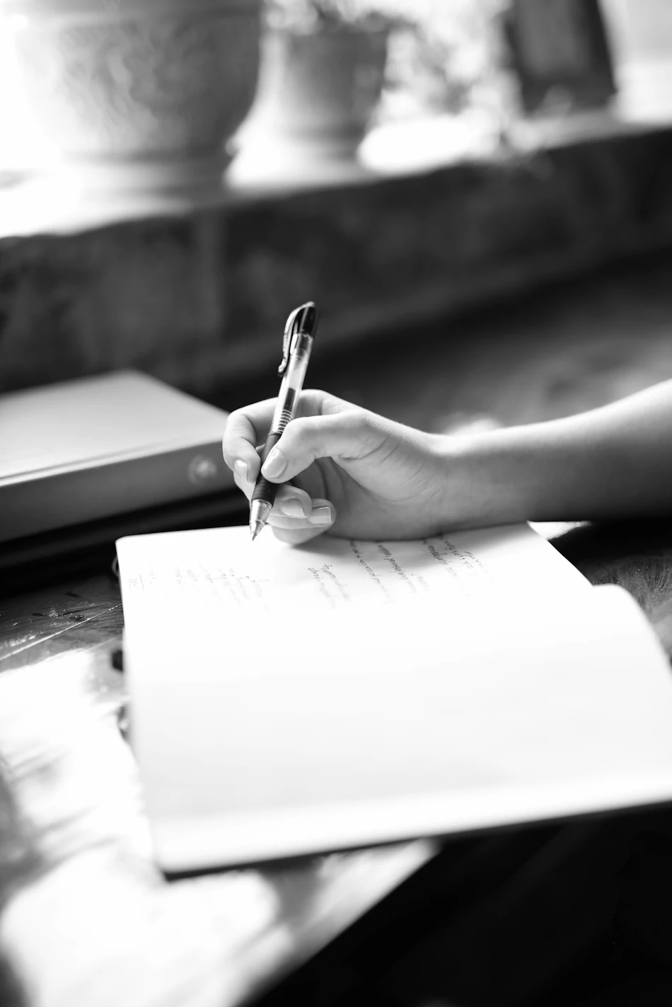 Manos tomando notas en una libreta junto a una ventana